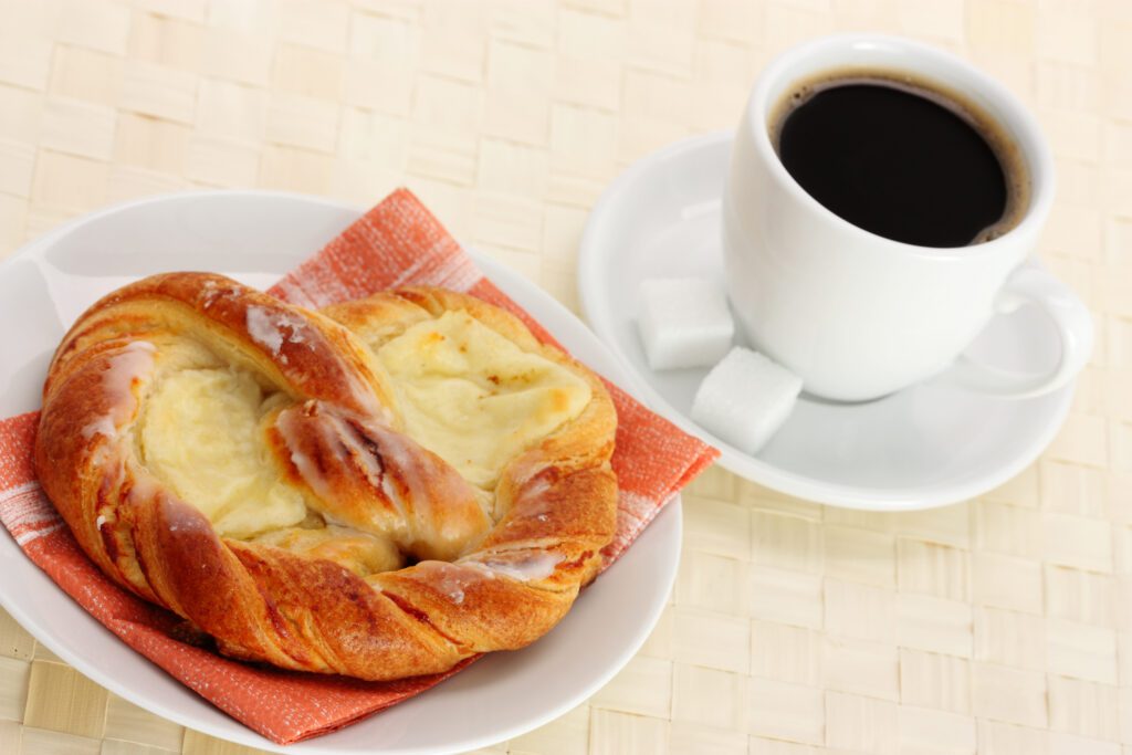 Freshly brewed coffee with sweet pastry on a breakfast table.
