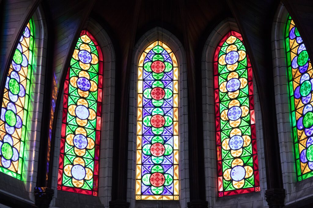 Gothic-style stained glass windows with vibrant floral and geometric designs in a cathedral.