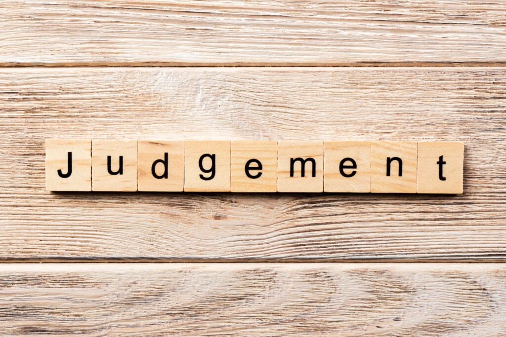 Wooden letter tiles on a table spelling the word 'Judgement'.