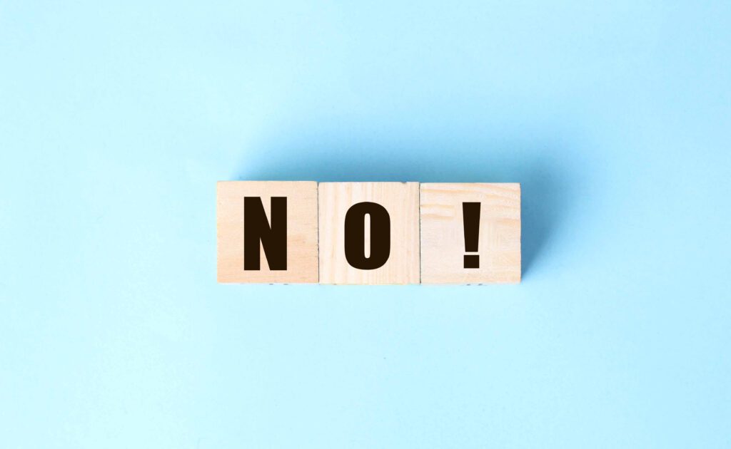 Wooden blocks spelling the word NO! on a light blue background.