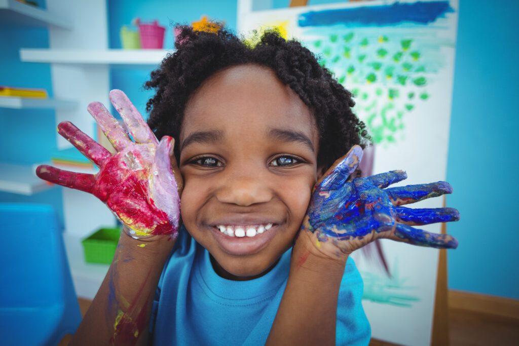 Happy child in Sunday school with painted hands enjoying a creative activity.