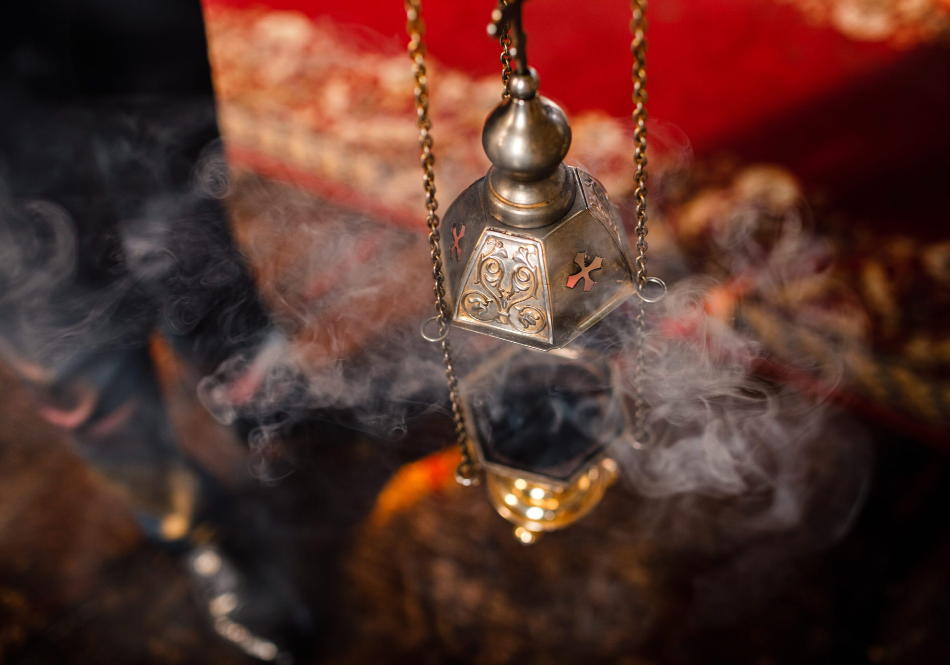 Liturgical brass censer releasing incense smoke in a church setting.