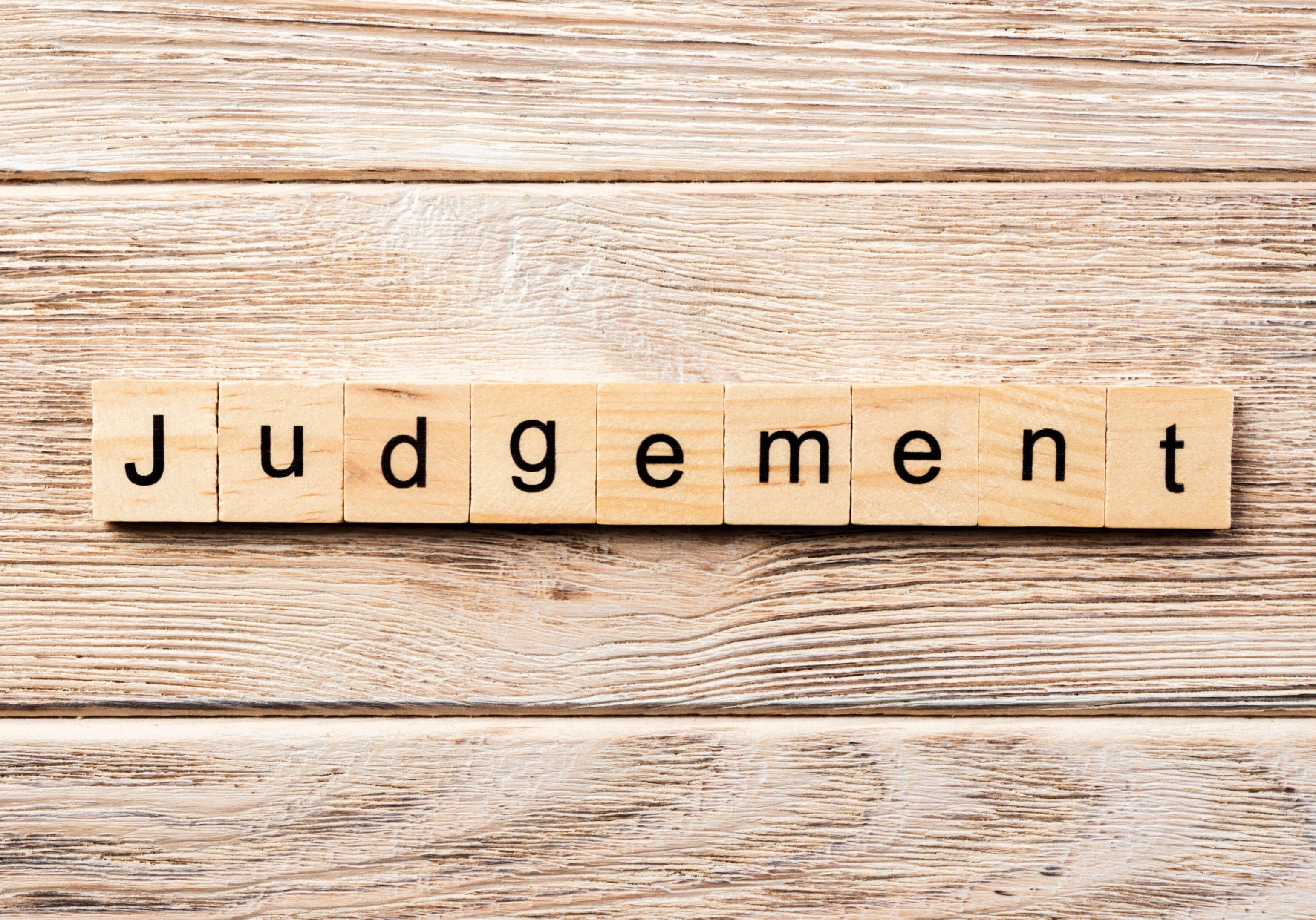 Wooden letter tiles on a table spelling the word 'Judgement'.