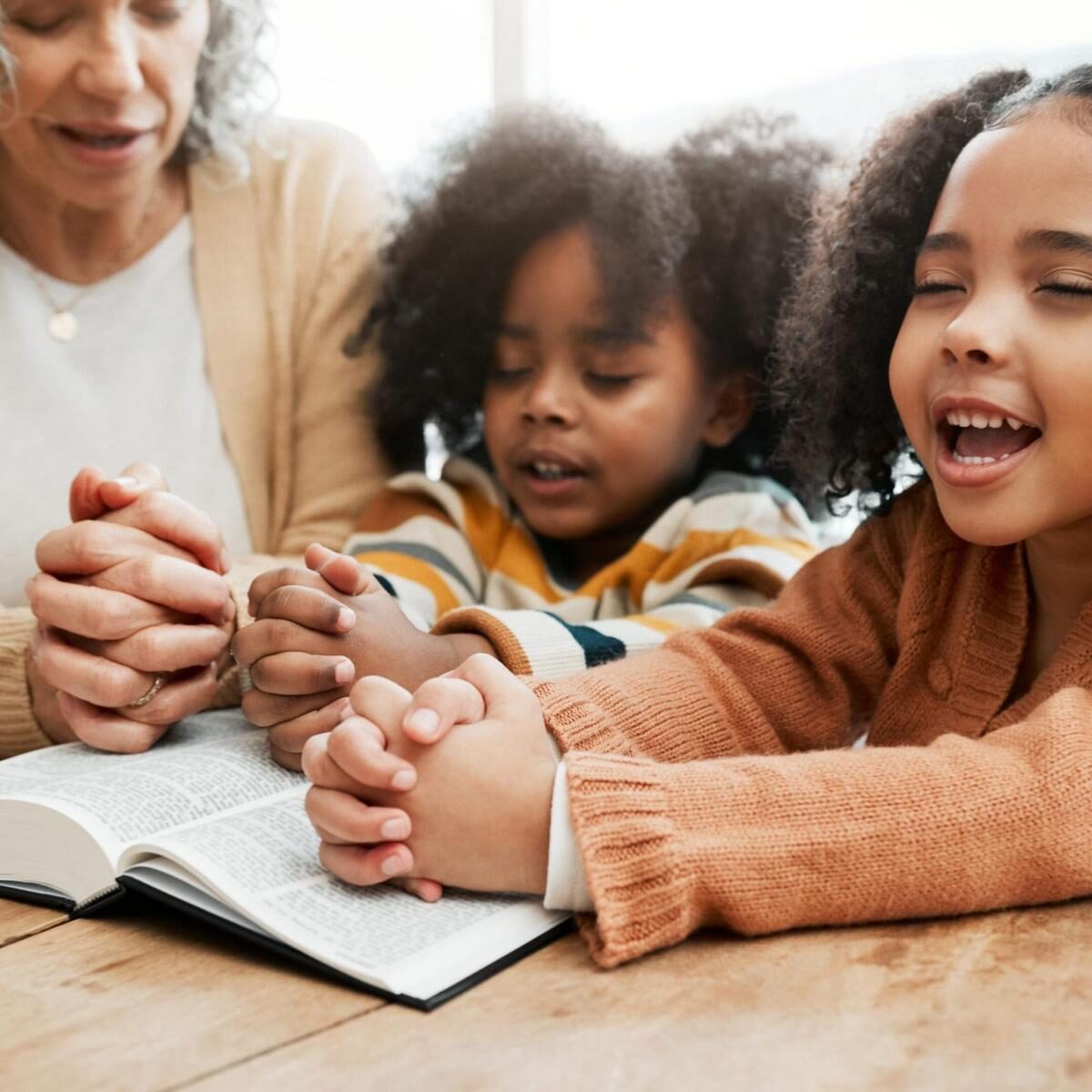 A family praying together surrounding an open Bible.