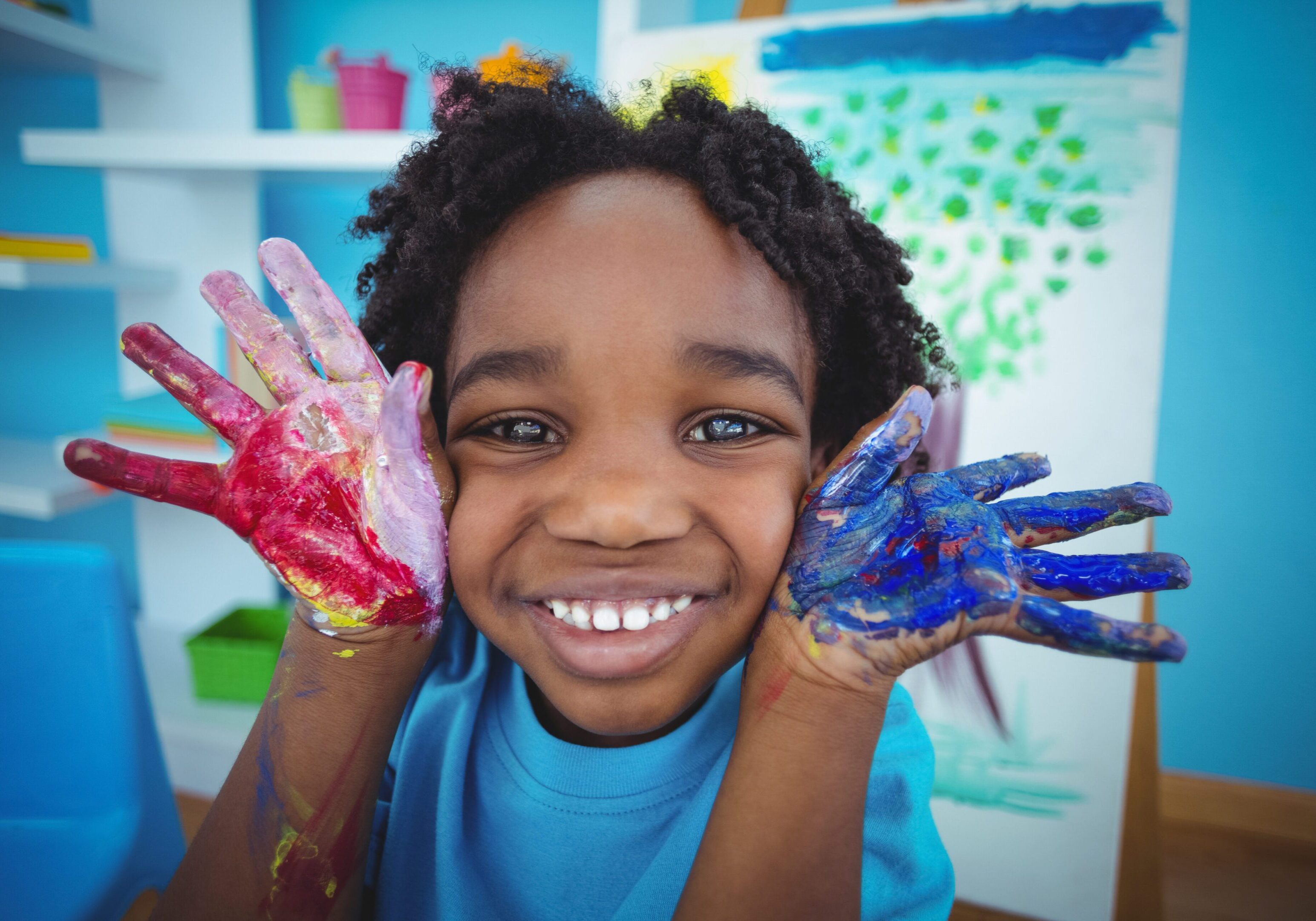 Happy child in Sunday school with painted hands enjoying a creative activity.